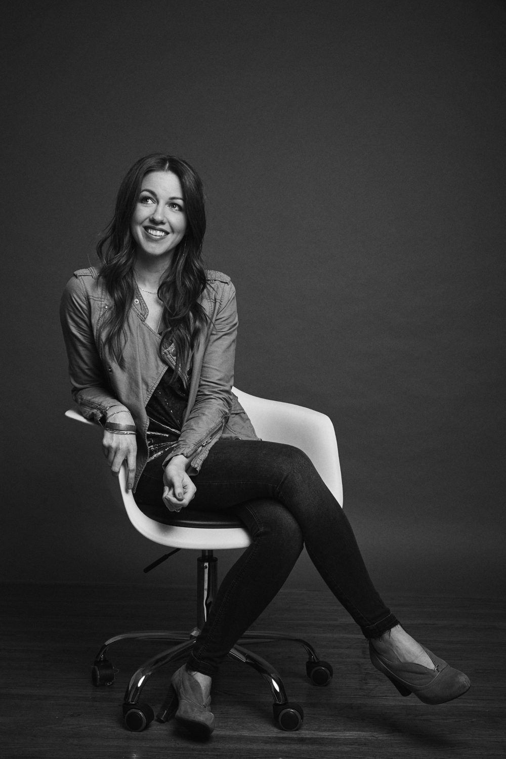 Shelby Rollins seated in a white chair, black and white studio portrait